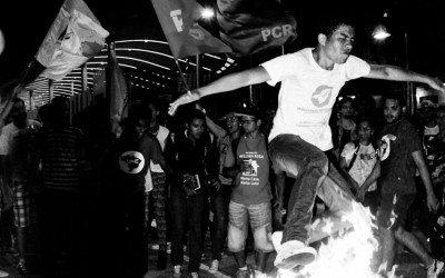 Protester jumping on the burning turnstile , Belo Horizonte, Brazil, 2014.