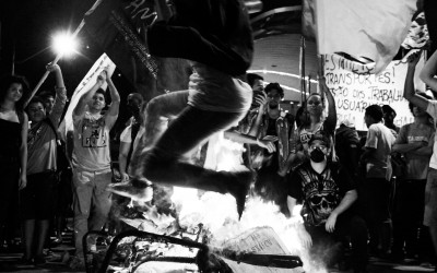 Protester jumping on the burning turnstile , Belo Horizonte, Brazil, 2014.
