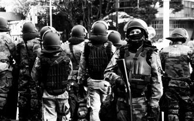 Polices in barriers protecting themselves against lacrimogenic gas, Belo Horizonte, Brazil, 2014.