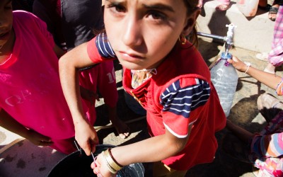 Young girl carries heavy water buckets back to her house in the Sharia Refugee Camp. In the camp’s entrance, visitors easily notice dozen of children filling water buckets. Many of them aren’t old enough to realize the seriousness of the situation. Since most of their families are numerous and weakened, they have to carry alone several water buckets through the huge camp’s corridors, Duhok, Iraq (Iraqi Kurdistan).